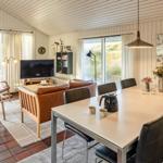 Wohn- und Essbereich mit braunem Sofa, Esstisch und großen Fenstern.