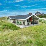 Moderne Strandvilla mit Terrasse und Grillplatz zwischen Dünen.