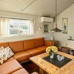 Wohnzimmer mit braunem Sofa, Holztisch und Kaminofen an Backsteinwand.