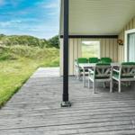 Terrasse mit Grill, Tisch und Stühlen. Grasige Dünen und dänische Flagge im Hintergrund.