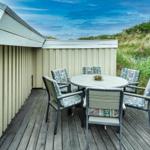 Terrasse mit runden Tisch und Stühlen neben Strandhütte