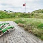 Terrasse mit zwei grünen Liegestühlen, Blick auf Grasland und dänische Flagge.