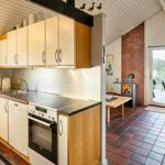 Küche mit Spüle, Herd und Waschmaschine. Wohnbereich mit Kamin und Sitzgelegenheiten.