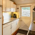 Küche mit Kühlschrank, Spüle und Fenster zur Außenseite.