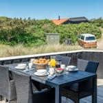 Terrasse mit Tisch und Stühlen für Frühstück mit Blick auf Grünflächen und Fahrzeug.