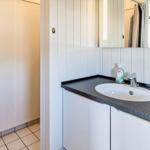 Waschbecken mit Spiegel und Seifenspender an grauem Arbeitsplatz.