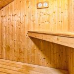 Sauna mit Holzwand, Sitzbank und Temperaturanzeige