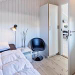 Schlafzimmer mit Bett, Stuhl und Kleiderschrank. Fenster mit Rollladen und Tür zum Flur.