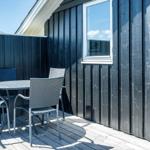 Terrasse mit Tisch und Stühlen vor schwarzem Holzhaus