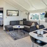 Wohnbereich mit Sofa, Esstisch und Kaminofen. Blick auf Schlafzimmer.