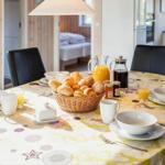 Runder Tisch mit Frühstück, Korb mit Brot, Gläser mit Saft und Tassen.