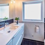 Badezimmer mit Waschbecken, Spiegel, Toilette und Fenster