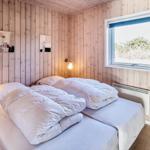 Schlafzimmer mit Holzwänden, Doppelbett und Fenster mit Blick auf Grünflächen.