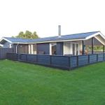 Moderne Ferienhaus mit Terrasse und Garten. Schwarze Holzverkleidung und blauer Dachziegel.