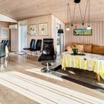 Wohn- und Essbereich mit Holzboden, Sofa, Essgruppe und Sessel. Küche im Hintergrund.