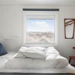 Schlafzimmer mit Bett, Fenster und Holzstuhl.