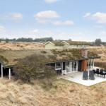Moderne Strandhaus mit grünem Dach und Terrasse im Dünenland.