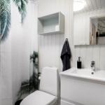 Badezimmer mit Toilette, Waschbecken und Duschvorhang mit Palmenmuster.