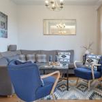 Wohnzimmer mit grauem Sofa, zwei blauen Sesseln und gemustertem Teppich.