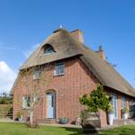Rotes Backsteinhaus mit Strohdach und Garten