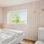 Bedroom with wooden walls, bed, and window with view of trees.