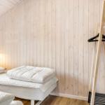 Room with wooden walls, bed, window, and coat rack.