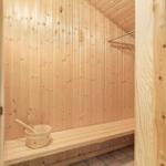 Sauna with wooden walls, bench, and wooden bucket.