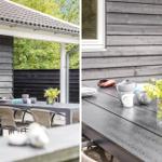 Terrace with table, chairs, plants, and mugs. Gray wooden walls and green trees in the background.
