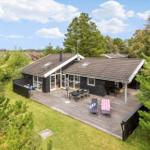 Modern wooden house with large deck and garden in green surroundings.