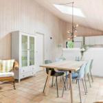 Dining area with table, chairs, and kitchen. Wall art and sideboard are visible.