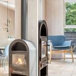Wood-burning stove, seating area, and window with view of trees.