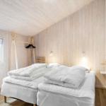 Bedroom with two beds, wooden walls, and window view.