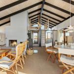 Living area with fireplace, dining table, and seating under wooden ceiling.