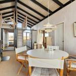 Round table with chairs, fireplace, and wooden ceiling in living area.