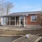 Haus mit Glasveranda, Terrasse und Garten. Holztisch mit zwei Tassen.