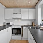 Küche mit weißen Schränken, dunklem Arbeitsplatz und Holzdecke.
