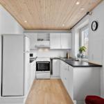 Küche mit weißer Einbauküche, Kühlschrank, Herd und Fenster
