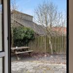 Durch die Tür ist ein Garten mit Holztisch und Zaun zu sehen.