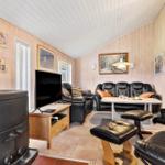 Wohnzimmer mit Holzwand, Sofa, Fernseher und Kaminofen.