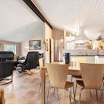 Essbereich mit Holztisch und Stühlen. Im Hintergrund Küche und Wohnbereich mit Ledersofas.