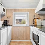 Küche mit weißen Schränken, Holzwand und Fenster
