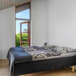 Schlafzimmer mit Bett, Fenster und Holzregal