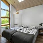 Schlafzimmer mit Doppelbett, großem Fenster und Holzdecke.