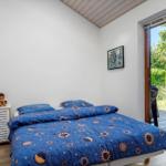 Schlafzimmer mit Bett, Nachttisch und Fenster zur Terrasse.