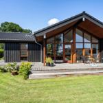 Moderne Holzhütte mit großem Glasbereich und Terrasse im Garten.