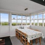 Esszimmer mit Tisch, Stühlen und Meerblick durch große Fenster.