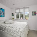 Schlafzimmer mit Bett, Fenster und Wandbildern.