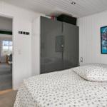 Schlafzimmer mit Bett, Kleiderschrank und Wandbild. Durchgang zur Küche und Terrasse.