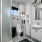 Badezimmer mit Toilette, Waschbecken und Dusche. Weiße Einrichtung und Fenster mit Blick.