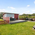 Rotes Ferienhaus mit Terrasse und Garten. Grill und Sitzgelegenheiten vorhanden.
